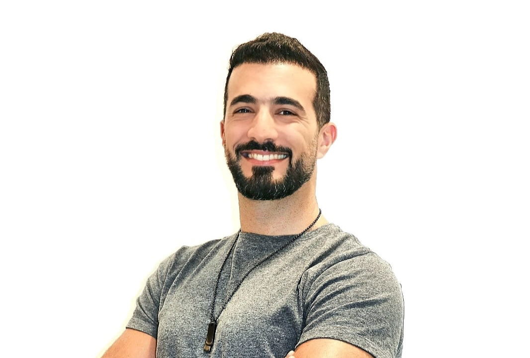 Man wearing a gray t-shirt with arms crossed on a white background
